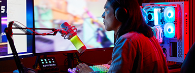 A gamer looks at multiple curved monitors surrounded by many RGB peripherals