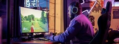 a gamer on his desk with PVP shooter game on his monitor at home