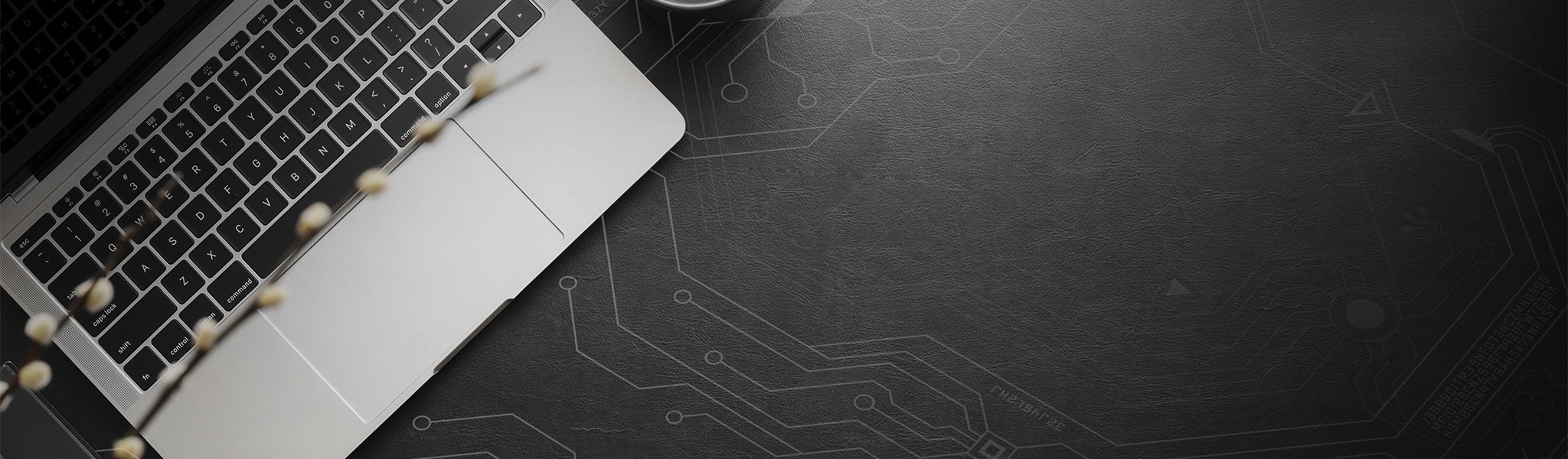 top view of a laptop on a dark desk with circuit board line illustrations